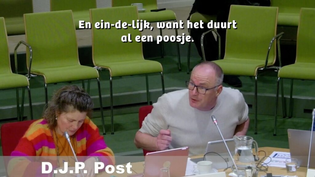 Man en vrouw in vergadering met groene stoelen op de achtergrond.