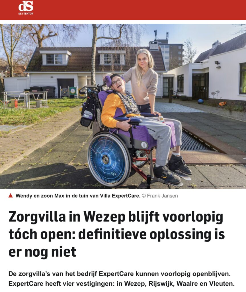 Een vrouw staat naast een jongen in een rolstoel in een tuin.